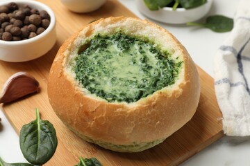 Delicious spinach sauce in bread bowl on white table, closeup