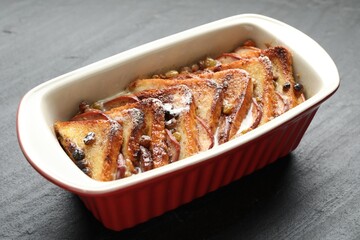 Freshly baked bread pudding in baking dish on grey textured table, closeup