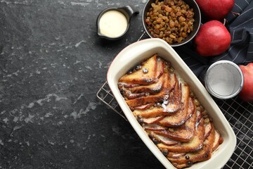 Freshly baked bread pudding in baking dish and products on grey textured table, flat lay. Space for...