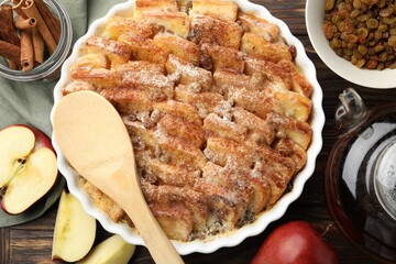 Delicious bread pudding with raisins, cinnamon and apples on wooden table, flat lay