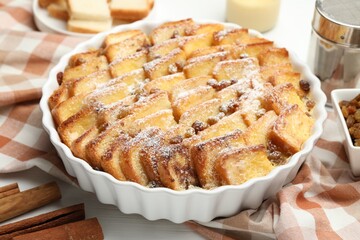 Delicious bread pudding with raisins and powdered sugar on table, closeup