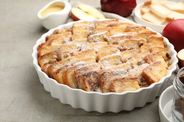 Delicious bread pudding with raisins, powdered sugar and apples on grey table, closeup