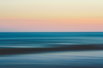 Blurred ocean waves stretch toward a pastel sunset sky.