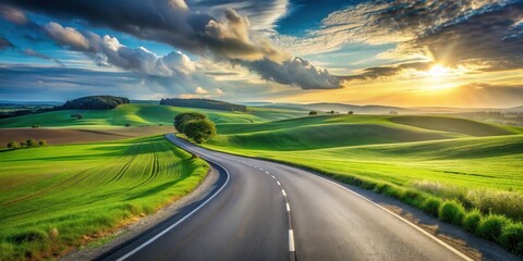 Naklejka premium Asphalt road curving through vibrant green rolling hills at sunset, a picturesque journey into nature's beauty.