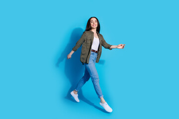 Confident young woman walking with a smile on a bright blue background
