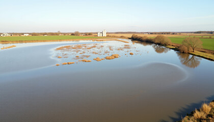 Fototapeta premium Expansive flooded farmland under clear sky post-storm, environmental impact