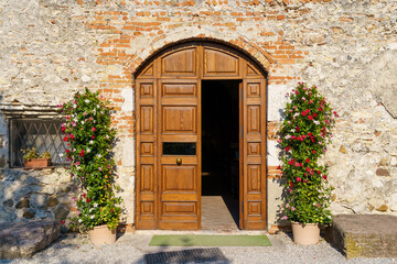 Wooden Doorway with Flowering Plants in Pots on Stone Wall in Italy