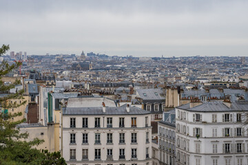 View of Paris rooftops under a cloudy sky in late afternoon light
