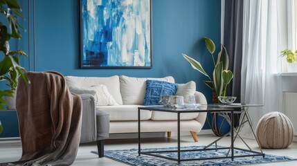 Living room interior with metal coffee table, grey armchair, white sofa, blanket, pillow, and large painting on blue wall