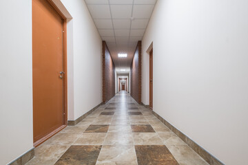 white empty long corridor with red brick walls and doors in interior of modern apartments or office