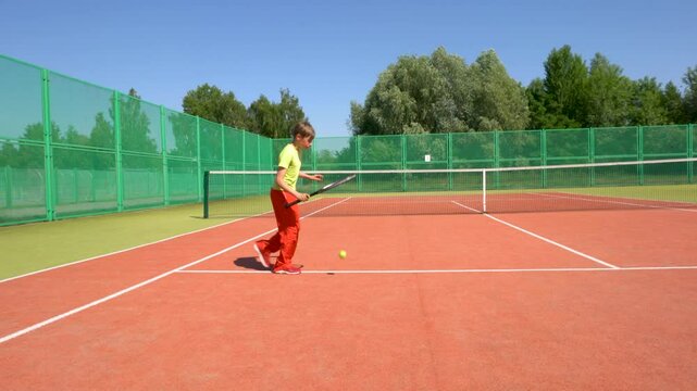 A teenage boy runs around the tennis court with a racket and hits the ball.