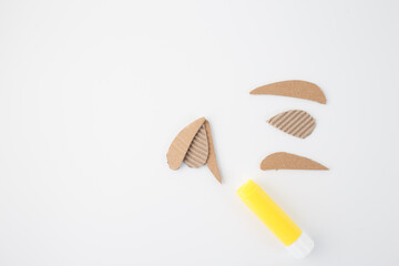 materials for a craft project, suggesting the assembly of the cardboard pieces using the glue stick. step in creative process