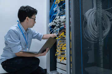 Computer engineer is setting up network in server room,Systems Maintenance Technician,Male engineer working in server room at modern data center