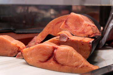 Close-up of fresh, large red swordfish slices displayed on a white board,  emphasizing healthy...