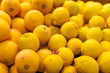 Bright yellow lemons displayed on a farmer's market stall, surrounded by fresh produce, embodying healthy living, nutrition, and organic choices