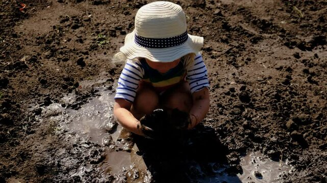 child dirty plays in mud. Selective focus.