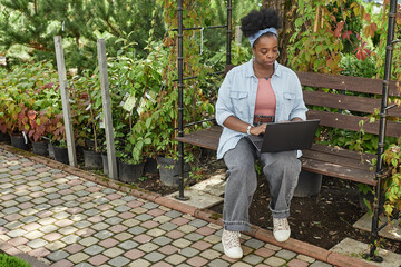 Full length shot of African American female landscape architect immersed in designing garden...