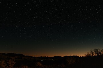 Night sky filled with stars over a desert landscape, showcasing distant mountains and a serene horizon