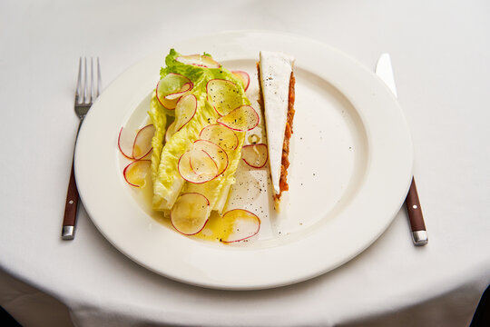 Brie cheese layered with onion marmalade. Served with summer salad greens. Restaurant serving, fancy restaurant.