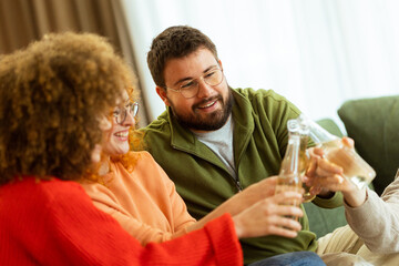 Friends sharing laughter and drinks together in a cozy living room during a joyful gathering