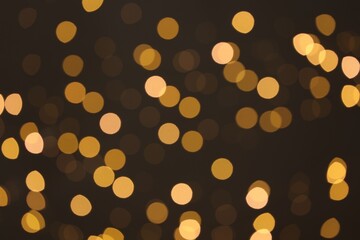 Blurred view of golden lights on dark background, bokeh effect