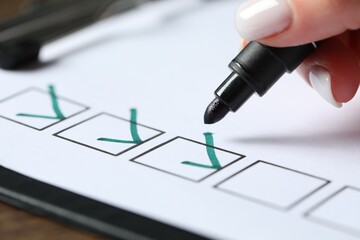 Woman checking box of paper form at wooden table, closeup