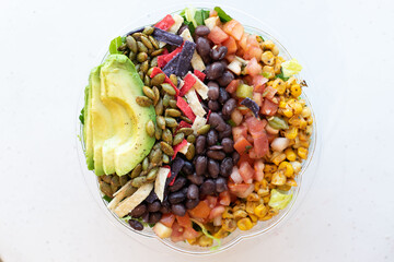 Southwest salad with black beans, roasted corn, avocado, tortilla strips, and pepitas in a clear bowl