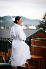Woman in white swimsuit enjoys a hot water vat surrounded by winter mountains and scenic views