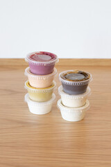 Stacked salad dressings in plastic cups on a wooden countertop with a clean white background