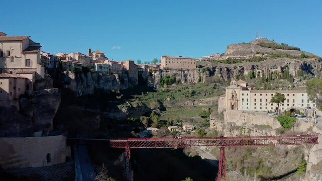 Quadcopter footage of a small town in a rocky area, view of a bridge connecting different parts of the city