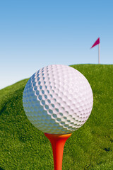 A golf ball on a tee with a flag in the background, set against a clear blue sky. 3d rendering