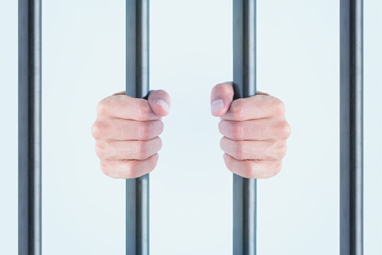 Human hands gripping metal bars, symbolizing prison, restriction, captivity, front view, white background. Minimal concept of isolation, criminal, conviction, repression or dungeon.