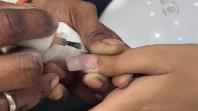 Nail Extension Application: A close-up shot captures the meticulous application of a nail extension, showcasing the precision and artistry involved in creating stunning nails.  