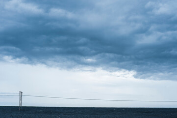 Power line stretches across vast Icelandic landscape under dramatic clouded sky