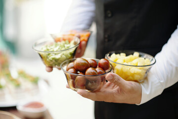 Waiter serving different appetizers in small bowls during banquet in the restaurant