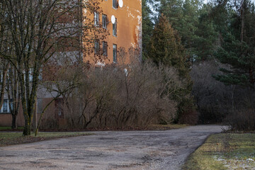 sunlit multi-storey house, soviet style, empty asphalt road, late autumn, sunny day, brown house