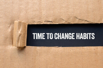Obraz premium Time to change habits message written on ripped torn cardboard paper on black background. Conceptual time to change habits symbol. Copy space.