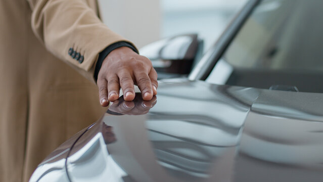 Male hand on new electric lead car headlight future of auto industry eco modern crossover automobile sale at dealership showroom. Unrecognizable african american business man buyer stroking vehicle