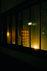Abstract night shot of illuminated glass windows with reflections of neon lights. The contrast between warm and cool tones creates a cinematic and mysterious atmosphere, 