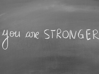 Fototapeta premium Motivational handwritten phrase 'You are stronger' on a blackboard background