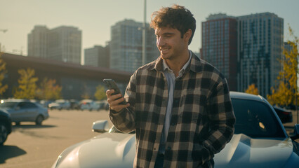 Caucasian man user driver using smartphone mobile phone messaging online in city outdoors happy...