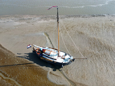 Aerial view of a classic sailboat lying on the tidal mudflats of the Wadden Sea, Holland - Powered by Adobe