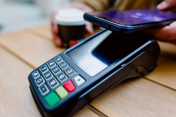 Person paying using smartphone nfc on pos terminal in a cafe