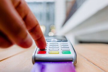Credit card payment, hand pushing red button on payment terminal