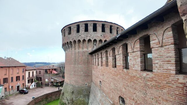 Cloudy sky over the medieval walls and the circular tower of the Rocca Sforzesca di Dozza, a fortress located in the village of Dozza, Emilia Romagna, Italy, dominating the surrounding landscape
