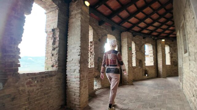 woman tourist walking inside the medieval Dozza castle in Italy, enjoying the ancient architecture and the atmosphere of the historical building