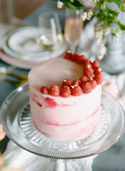 Delicious raspberry cake with elegant decoration on a festive table set for a celebration