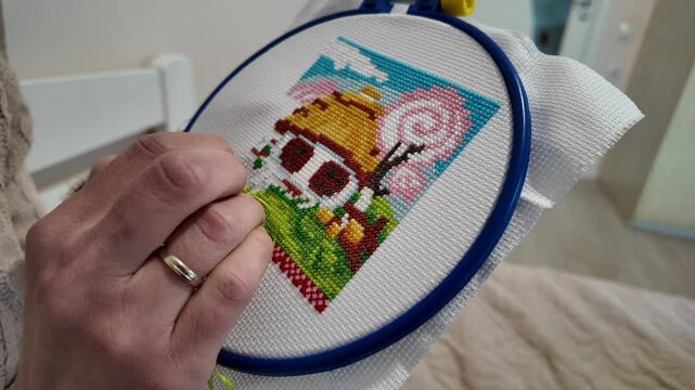 Woman carefully holding an embroidery hoop while creating a detailed stitched pattern