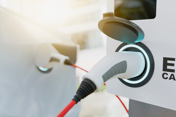 Close-up of an electric vehicle charging station with a modern connector, sunlight glinting off the...