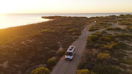 Aerial view of serene mangrove bay with a winding road and a campervan at sunset, Western Australia, Australia.